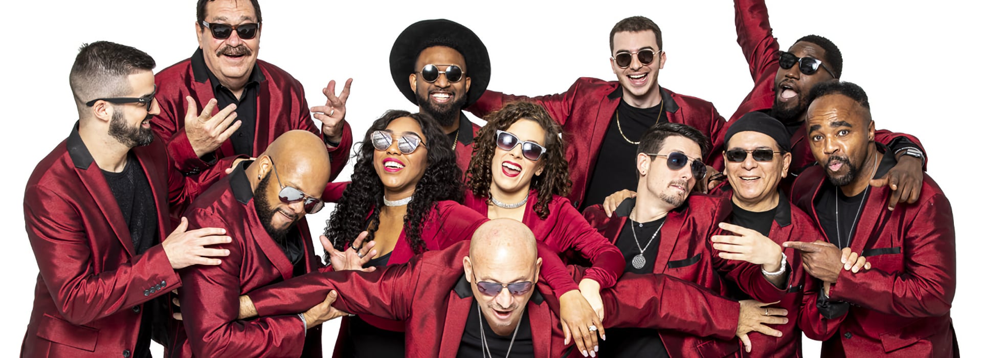 Group of people in red jackets smiling and posing playfully against a white background.