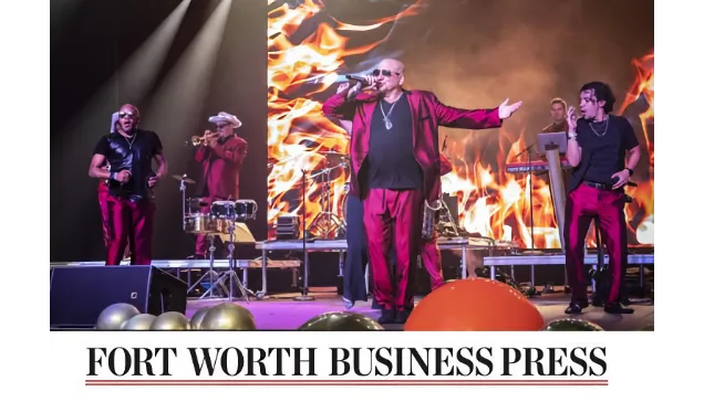 Band in red suits performing onstage with fire graphics in the background.