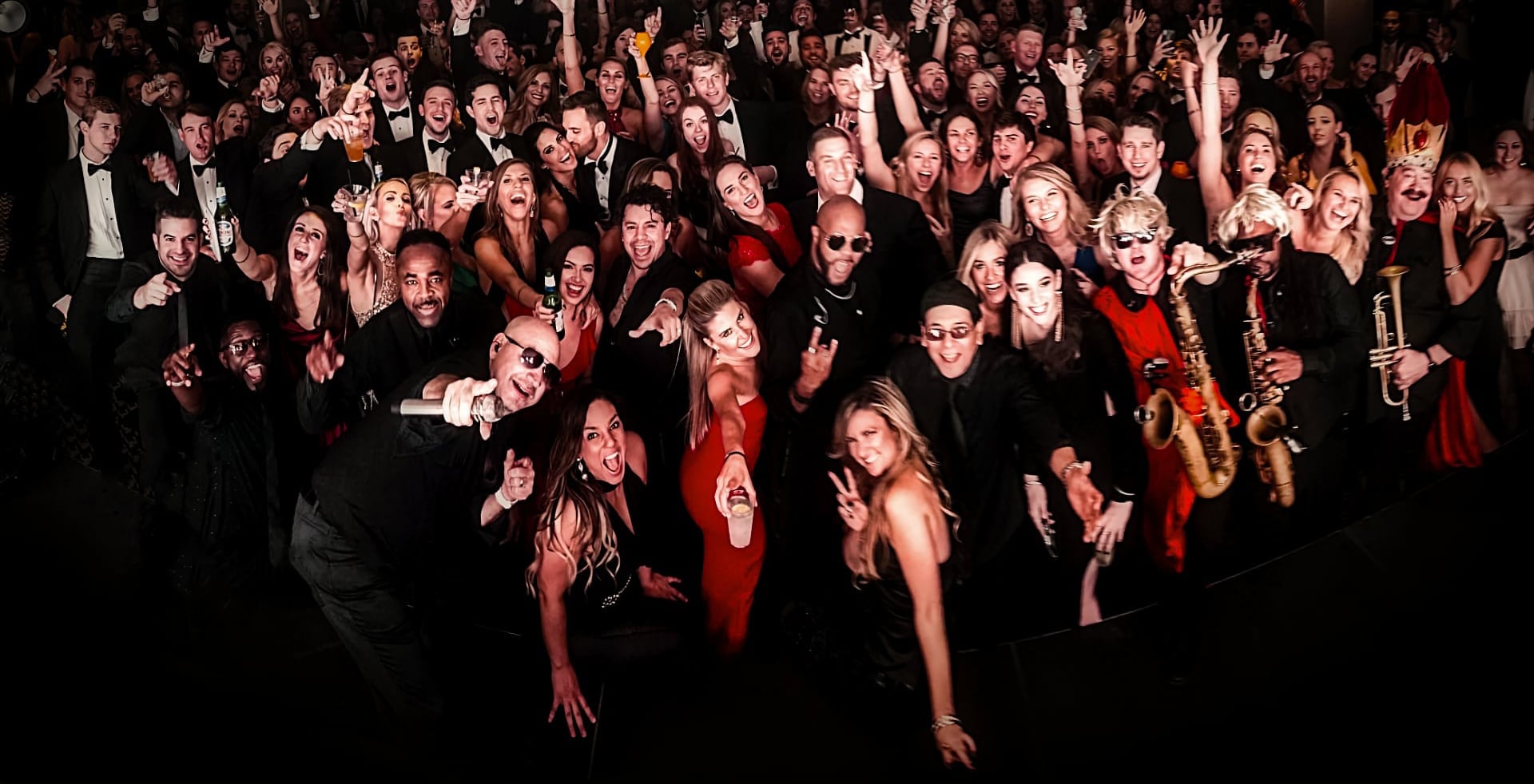 Large group of people dressed in formal attire posing and smiling for a group photo.