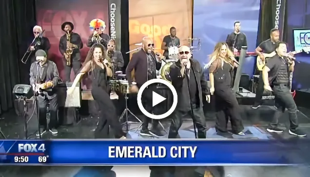 Band performing live on a news studio stage with "Emerald City" text on screen.