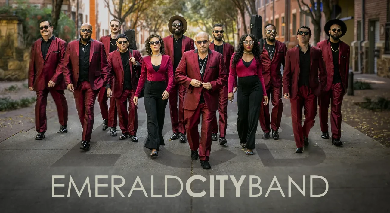 Twelve people in matching red suits walking confidently down a street.