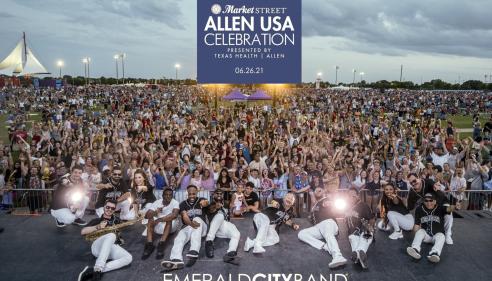 members of Emerald City Band laying on stage in front of a large crowd