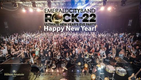 Large cheering crowd at a New Year’s Eve concert with bright stage lights.