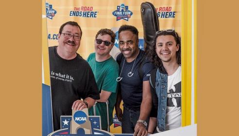 Four smiling men pose together at an NCAA Final Four Houston 2023 basketball event display.