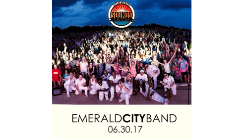 Large crowd cheering outdoors at dusk with Emerald City Band and event date text below.