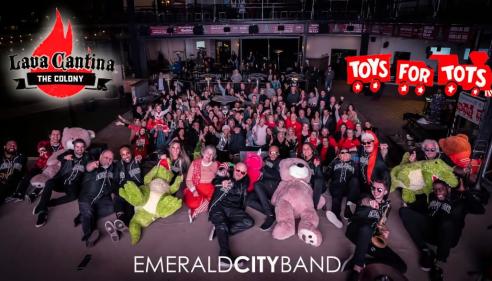 Large group of people posing together, some in costumes, with event logos in the background.