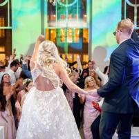 Bride and groom celebrate on a lively dance floor, surrounded by cheering guests.
