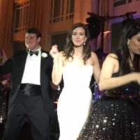 Bride and groom dancing on stage with a singer performing at a wedding reception.
