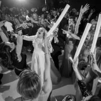 Crowd dancing and celebrating with glow sticks at a lively party.