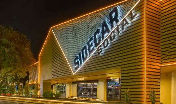 Sidecar Social building at night with illuminated signage and trim.
