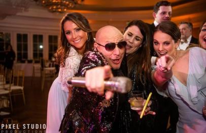 Group of people dressed up, smiling and posing together at a lively indoor party.