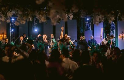 Band performing on stage at a lively indoor event with a dancing crowd.