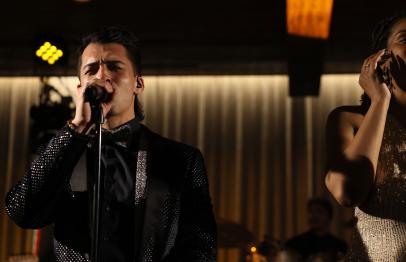 Two singers performing on stage under warm lighting.