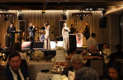 Band performing on stage at an elegant indoor wedding reception with guests dining.