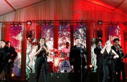 Band performing on stage with colorful lights and musicians playing instruments.