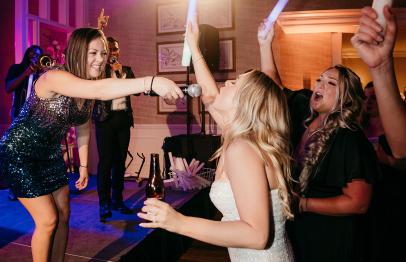 Women singing and cheering at a lively party with colorful lights.