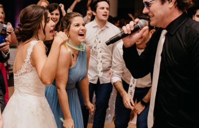 Wedding guests dancing and singing with a man singing into a microphone.