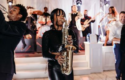 Jazz band performing on stage with saxophone and trumpet players in the foreground.