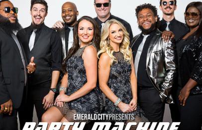 Nine people in coordinated black and silver outfits smiling in a group studio photo.
