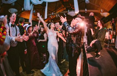 Bride dancing joyfully with guests at a lively wedding reception.