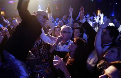 Performer reaching out to excited crowd at a lively indoor concert or event.