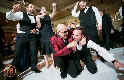People dancing and singing joyfully at a formal event, with lively expressions and gestures.