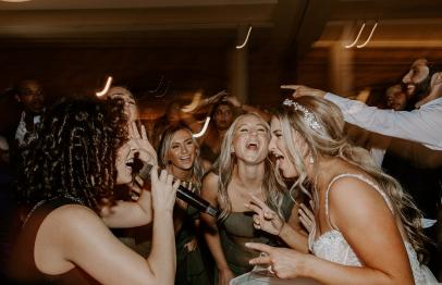 Bride and guests singing and dancing joyfully at a wedding reception.