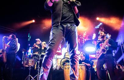 Singer and band performing on stage with colorful lights and instruments.