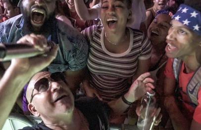 Singer performing with excited crowd at a lively concert.