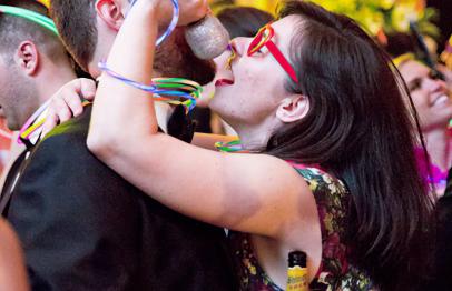 Woman in red glasses playfully singing into a microphone at a lively party.