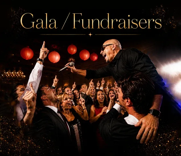 Man singing to enthusiastic crowd at a festive gala with red lights and decorations.