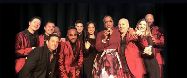 Members of Emerald City Band on stage with Oprah Winfrey