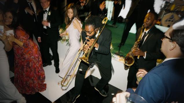 Musicians playing trombone and saxophone as people in formal wear dance nearby.