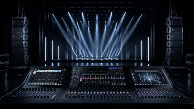 Sound mixing console in front of a stage with dramatic blue spotlights.