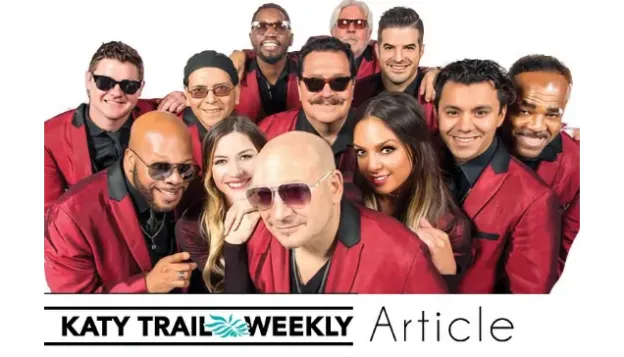 Group of people in red jackets smiling together, some wearing sunglasses.
