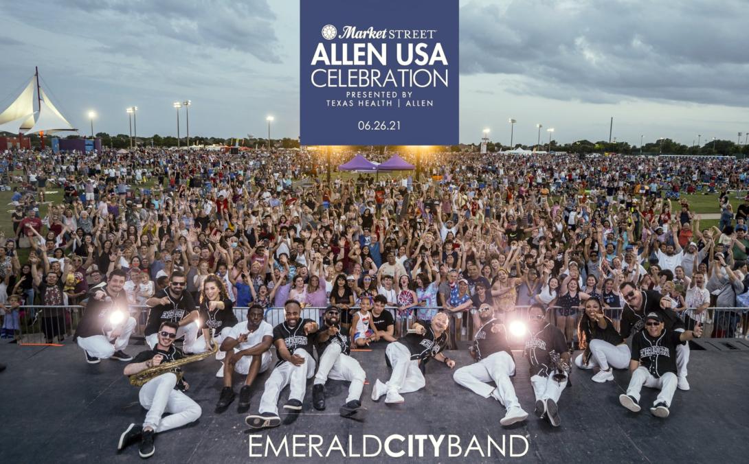 members of Emerald City Band laying on stage in front of a large crowd