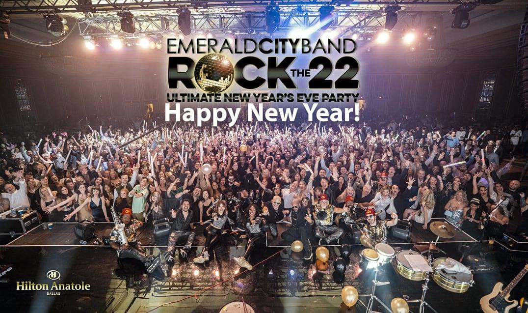 Large cheering crowd at a New Year’s Eve concert with bright stage lights.
