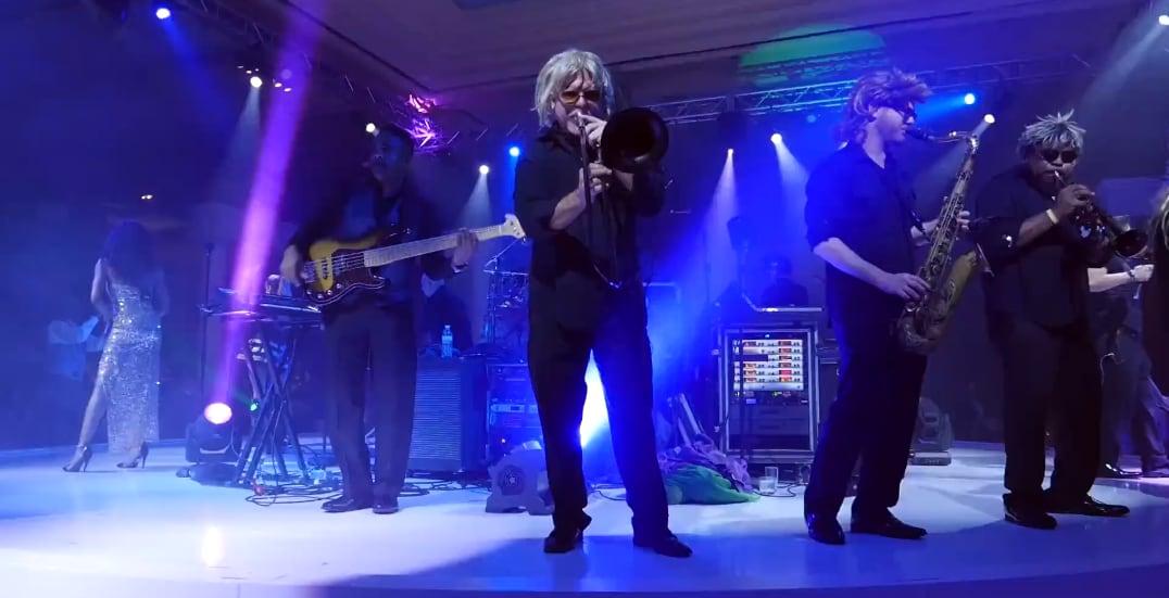 Band performing on stage with colorful lighting and fog effects.