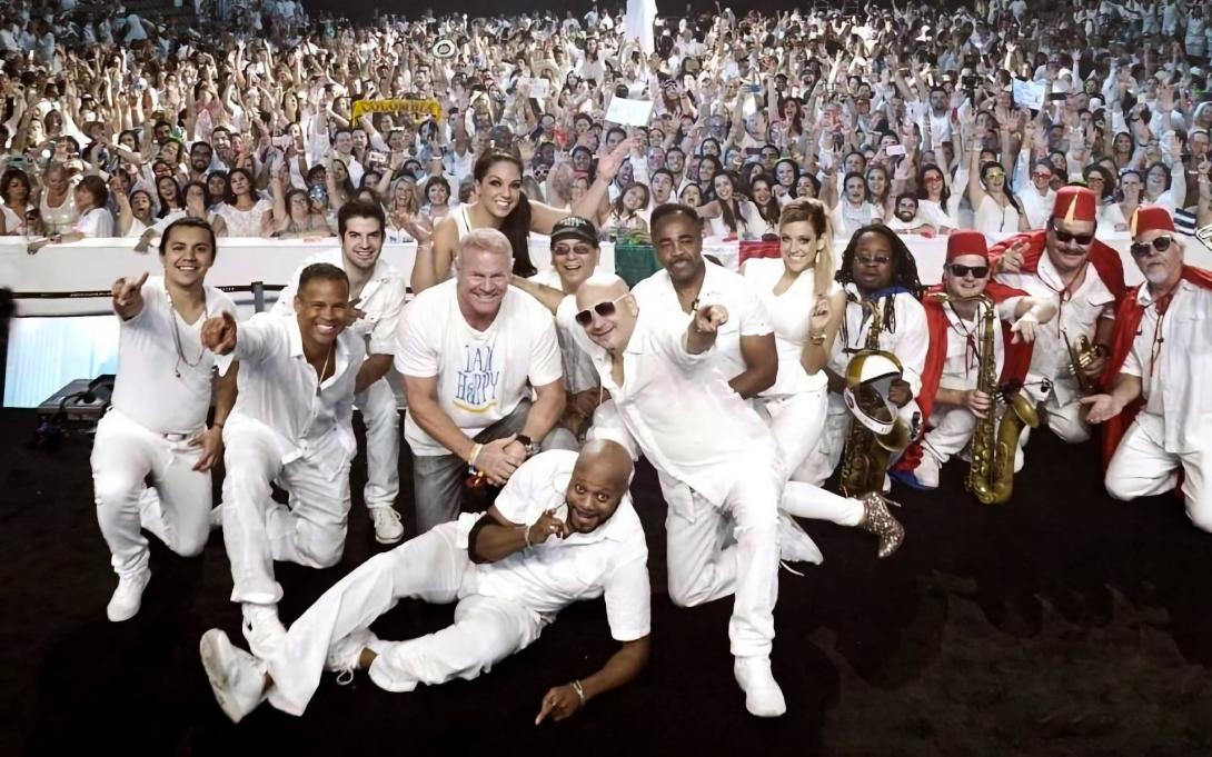 Members of Emerald City Band standing in front of a large crowd all dressed in white