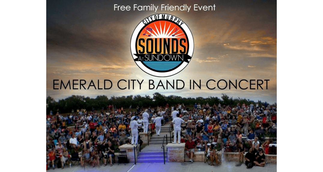 Outdoor concert with a band performing on stage and a large seated audience at sunset.
