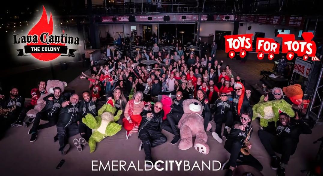 Large group of people posing together, some in costumes, with event logos in the background.