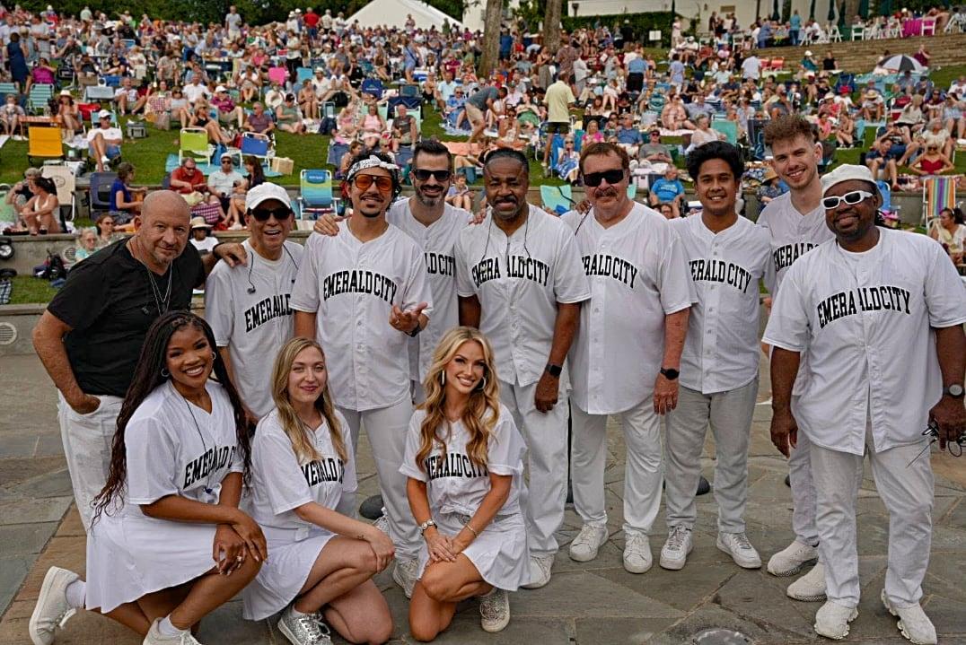 Band members standing together onstage in front of a crowd.